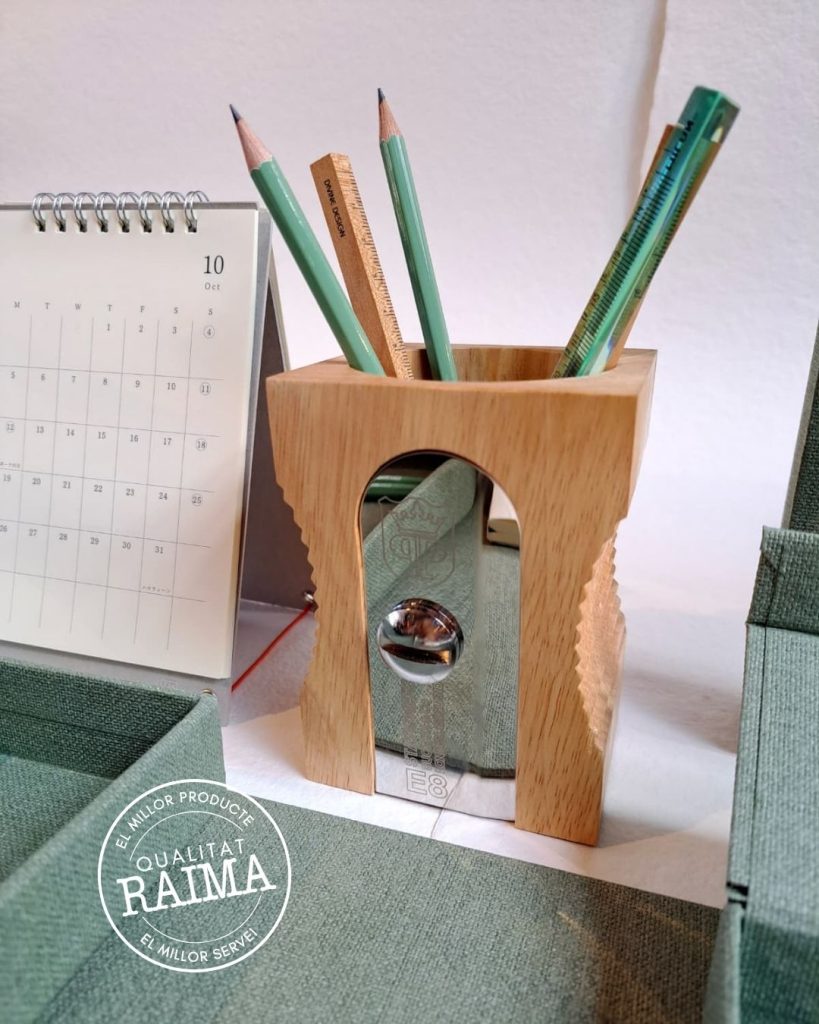 Porta-llapis de fusta en forma de maquineta, de color marró clar, amb diversos llapis i bolígrafs al seu interior.
Com organitzar l’escriptori amb accessoris de Bigso